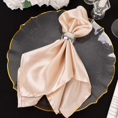 Elegant peach satin napkin with silver ring on a decorative plate.