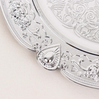Ornate silver serving platter with intricate floral engravings.
