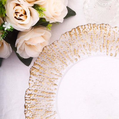 Elegant glass plate with gold detailing beside soft pink roses.