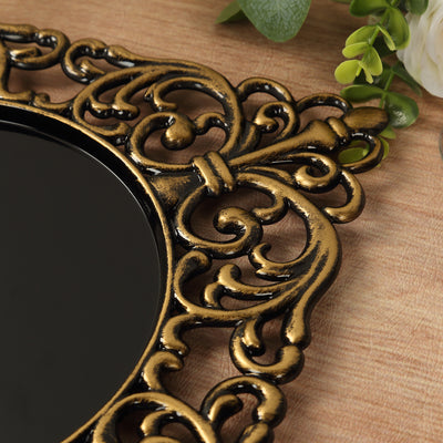 Ornate gold-framed mirror with intricate detailing on a wooden surface.