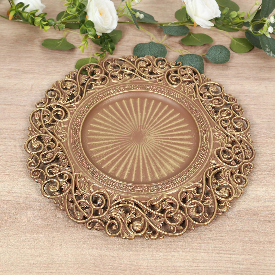 Ornate decorative gold plate with intricate floral design on wooden surface.