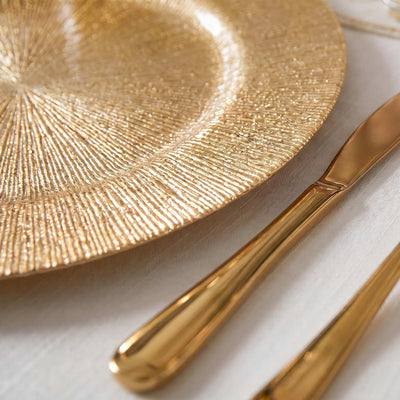 Gold textured dinner plate with matching gold cutlery on a white table setting