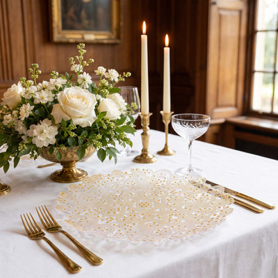 Elegant white and gold table setting with floral centerpiece and lit candles