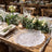 Rustic wedding table setting with white roses, greenery, and elegant glassware
