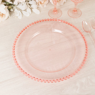 Pink decorative charger plate with beaded edge on a light wood surface.