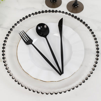 Elegant black cutlery on a decorative plate with a gold rim.