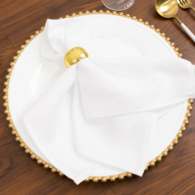 Elegant white napkin with gold ring on a decorative plate.