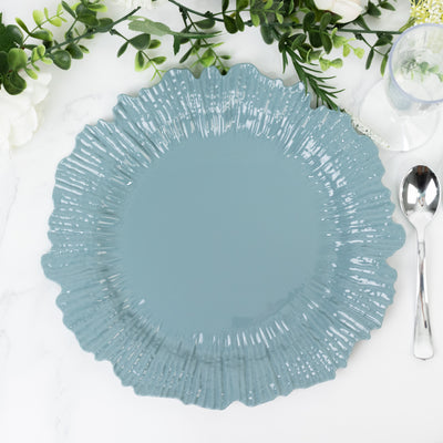 Blue decorative plate with a ruffled edge on a marble surface.