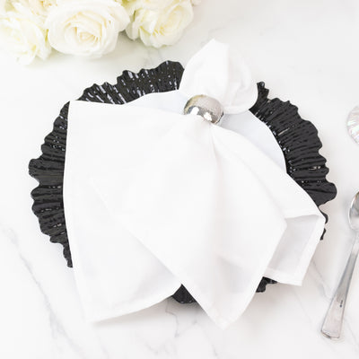 Elegant black plate with white napkin and silver ring, styled for dining.