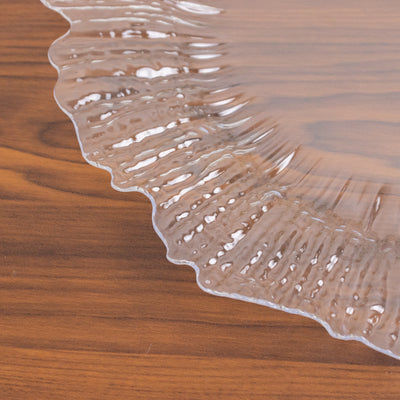 Clear decorative plate with a ruffled edge on a wooden table.
