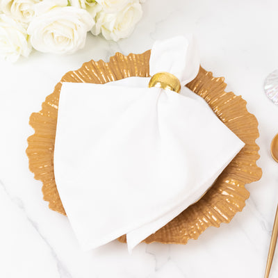 Elegant white napkin with gold ring on a decorative gold plate.