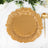 Gold decorative plate with a ruffled edge on a marble surface.