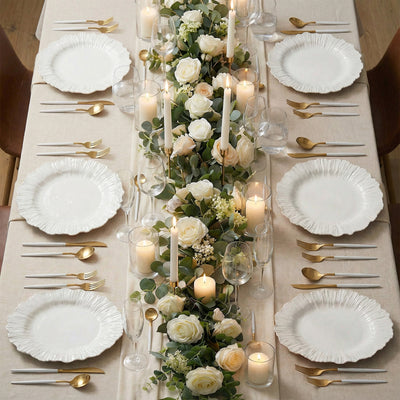 Elegant dinner table setting with white plates, candles, and floral centerpiece.