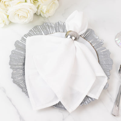Elegant white napkin with silver ring on a decorative silver plate.