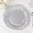 Silver decorative plate with a ruffled edge on a marble surface.