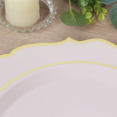 Pink plate with yellow trim on a wooden table with candle and greenery.