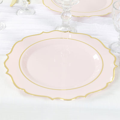Pink scalloped plate with gold trim on a white table setting.