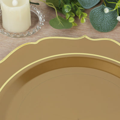 Gold rimmed decorative plate on a wooden table with greenery and a candle.