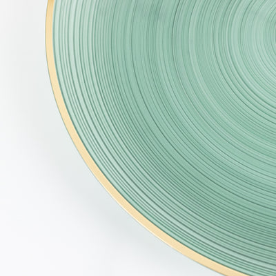 Green textured plate with gold rim on a plain background
