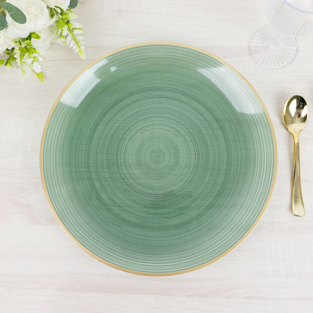 Green decorative plate with a gold rim on a light wooden table.