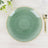 Green decorative plate with a gold rim on a light wooden table.