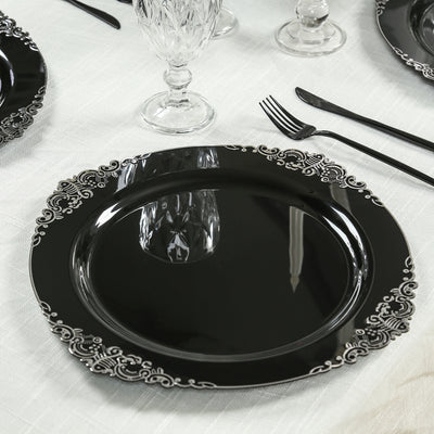 Elegant black dinner plate with decorative silver rim on a table setting.