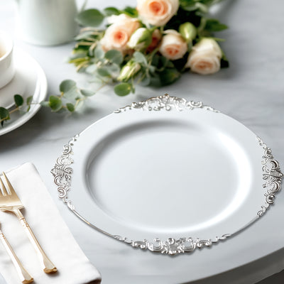 Elegant white plate with ornate silver detailing on a marble table.