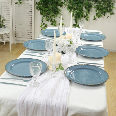 Elegant blue dinner plates set on a beautifully arranged table with candles and greenery.