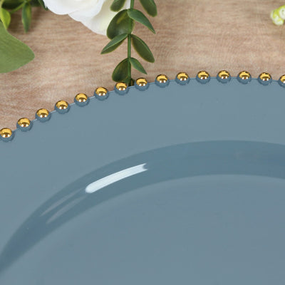 Blue decorative plate with gold bead trim on a textured surface.