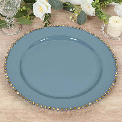 Blue decorative plate with gold bead trim on a wooden table.