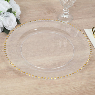 Clear charger plate with gold beaded trim on a wooden table.