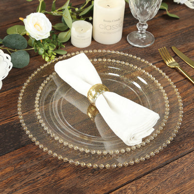 Elegant clear glass charger plate with beaded rim and white napkin.