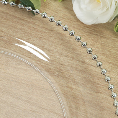 Clear glass plate with beaded silver rim on a textured wooden surface.
