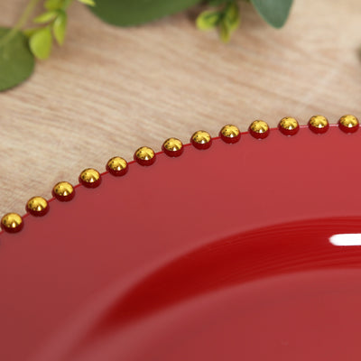 Red decorative plate with gold beaded rim on a wooden surface.