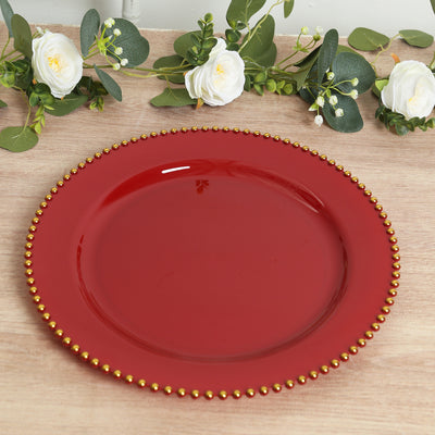 Red decorative plate with gold beaded rim on a textured surface.