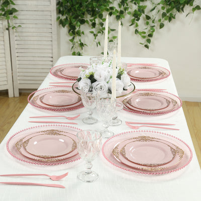 Elegant pink table setting with plates, glasses, and floral centerpiece.