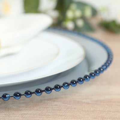 Blue beaded charger plate with white dinnerware in a styled setting.