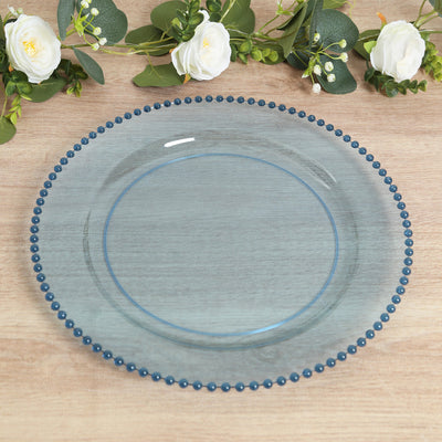 Blue beaded charger plate on a wooden surface with floral accents.