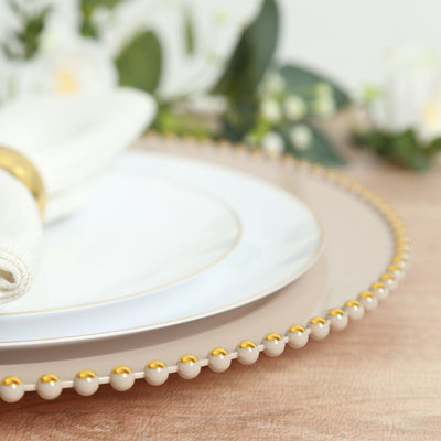 Elegant dinnerware set with gold accents and textured napkin on wooden table.