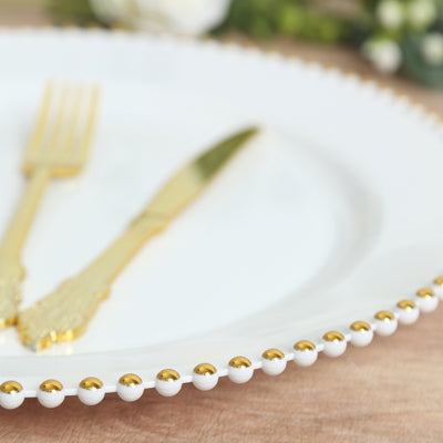 Elegant white plate with gold beaded rim and gold utensils.