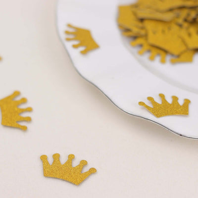 Gold crown confetti on a white plate, ideal for party decorations.