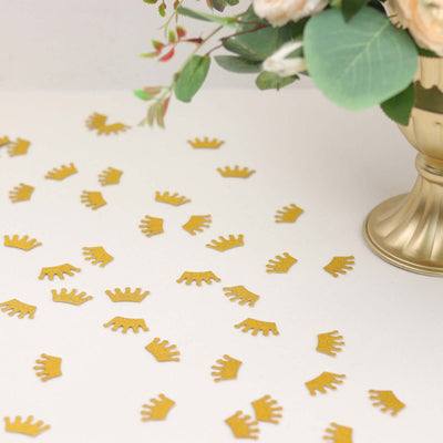 Gold crown confetti scattered around a decorative vase with flowers.