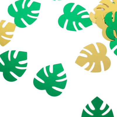 Colorful paper monstera leaf confetti scattered on a white background.