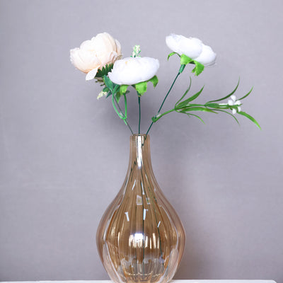 Glass vase with artificial flowers in soft pastel colors.