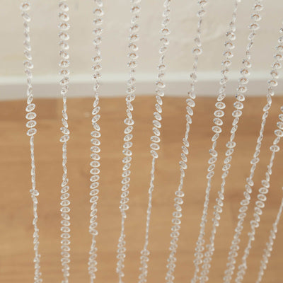 Clear beaded curtain strands on a wooden floor.