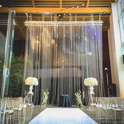 Elegant wedding ceremony setup with floral arrangements and draped backdrop.
