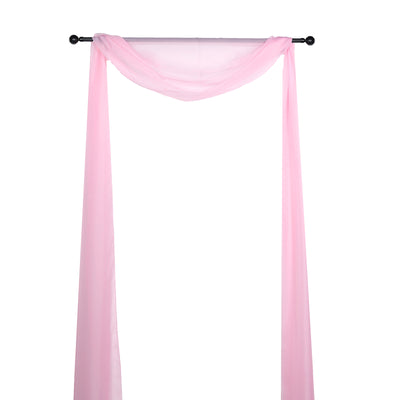 Pink sheer drapery fabric hanging on a black rod against a white background