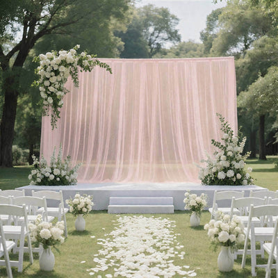 Elegant outdoor wedding ceremony setup with pink drape and white floral decor
