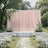 Elegant outdoor wedding ceremony setup with pink drape and white floral decor