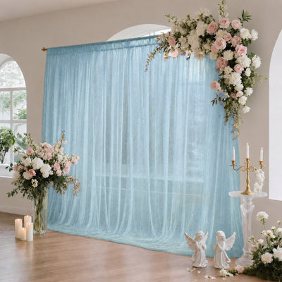Elegant wedding backdrop with blue sheer curtain, floral arch, and candles